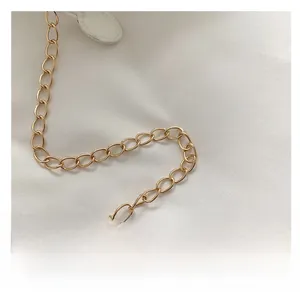 Detail of a golden chain strap with metal oval links and a white circular connector