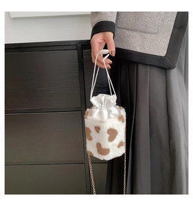 Detail of heart-shaped faux fur bucket bag with golden chain strap and drawstring closure