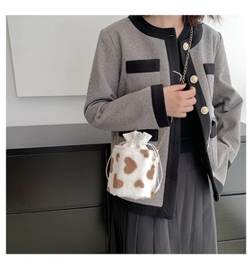 Detail of plush drawstring bucket bag with heart pattern and golden chain strap on model