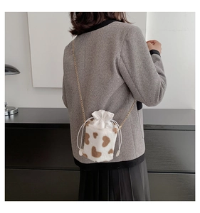 Detail of plush cow print bucket bag with heart pattern and golden chain strap