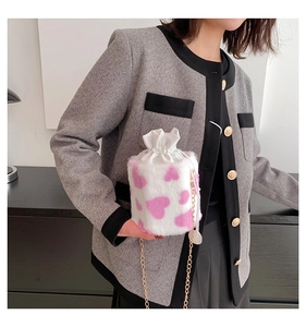Pink heart patterned plush bucket bag with golden chain strap shown on model's shoulder