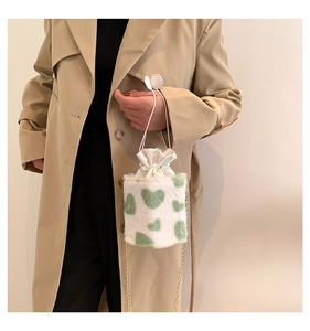 Detail of plush cow print bucket bag with green hearts and gold chain strap