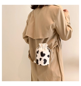 Detail of cow print plush bucket bag with golden chain strap on a trench coat