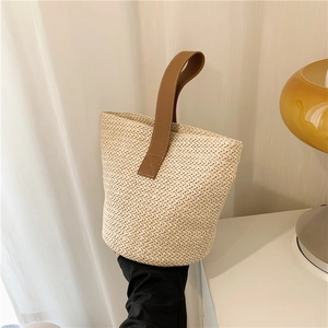 Beige straw woven bucket bag with brown leather handles and large capacity design