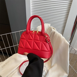 Elegant red quilted shell bag with golden zipper and detachable strap held in hand