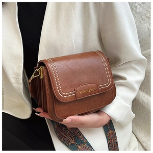 Dettaglio borsa vintage marrone con ampia tracolla etnica e fibbia in metallo dorato