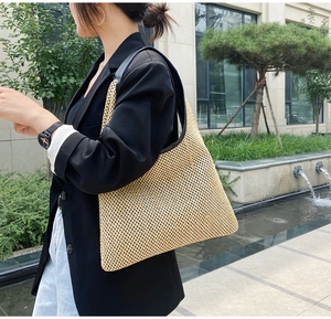 Detail of woven straw tote bag with black leather straps shown on model side view
