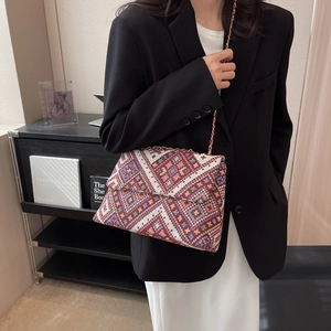 Ethnic style woven crossbody bag with geometric patterns and leather chain strap on model