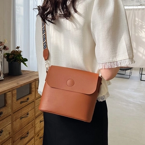 Sac seau en cuir marron avec bandoulière large jacquard porté par un mannequin