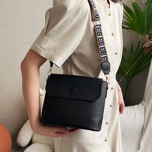 Sac seau rétro en similicuir noir avec bandoulière jacquard porté par un mannequin
