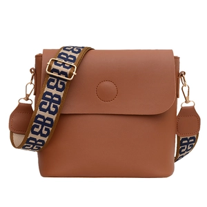 Sac seau minimaliste en cuir marron avec large bandoulière et finitions dorées