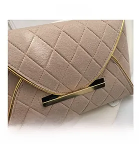 Détail de pochette enveloppe matelassée marron clair avec boucle dorée et tissu texturé