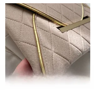 Gros plan sur le tissu matelassé et les finitions dorées de cette pochette enveloppe