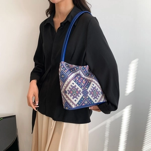 Ethnic style woven bucket bag with geometric patterns and blue leather straps