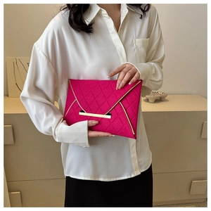 Détail d'une pochette enveloppe rose fuchsia avec matelassage et fermoir en métal doré