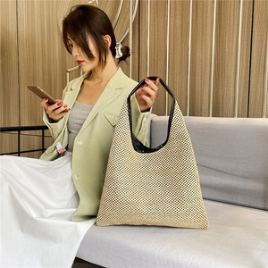 Stylish beige woven straw tote bag with black leather handles for summer fashion