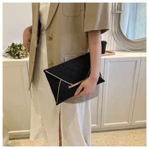 Gros plan détaillé de la pochette enveloppe noire avec motif matelassé et bordure dorée