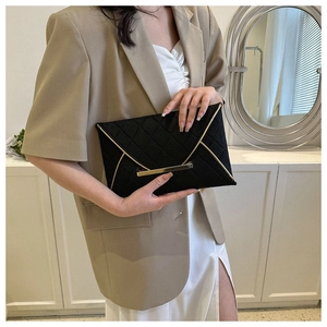 Détail d'une pochette enveloppe noire avec motif matelassé et bordures en métal doré chic
