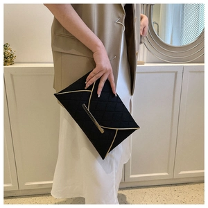 Détail de la pochette enveloppe matelassée noire avec bordure dorée élégante et rabat en V