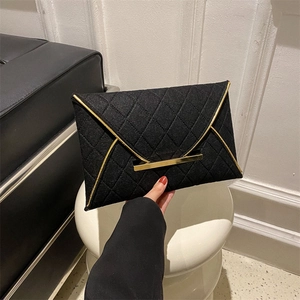 Détail d'une pochette enveloppe matelassée noire avec bordure dorée élégante à la main
