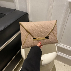 Détail de la pochette enveloppe beige avec motif matelassé et bordure en métal doré chic