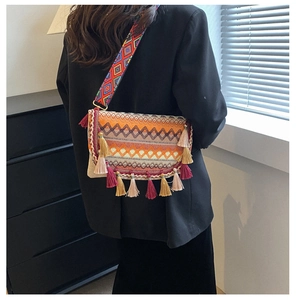 Detail of bohemian cross-body bag featuring colorful geometric patterns and fringe