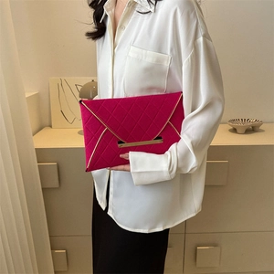 Pochette enveloppe matelassée fuchsia avec bordure dorée tenue par un mannequin