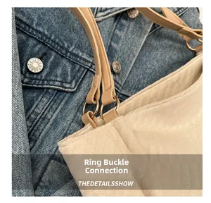 Detail of gold metal ring connecting brown leather strap to beige corduroy tote bag