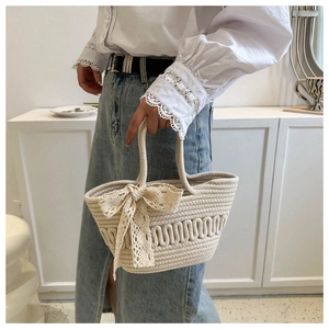 Detail of hand-woven straw tote with elegant lace bow and wave pattern texture