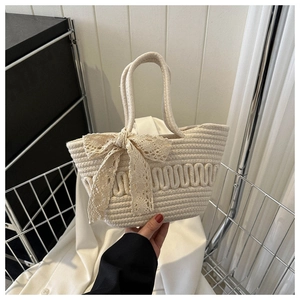 Detail of hand-woven cream tote bag featuring relief textures and delicate lace bows