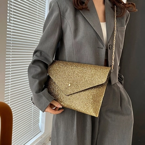 Elegante pochette a busta in paillettes dorate con tracolla a catena indossata da modella