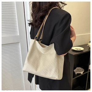 Detail view of a cream tote bag with textured fabric and metallic ring accents