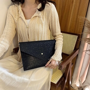 Elegante pochette a busta nera glitterata con catena dorata indossata da modella