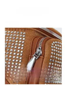 Detail of silver zipper closure on brown suede bag with silver rivet embellishments
