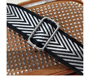 Detail of silver rhinestone embellishments on brown suede bag with woven shoulder strap