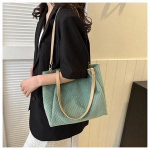 Detail of light green checkered tote bag with brown leather straps and gold hardware