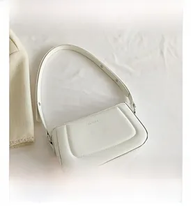 Detail of white leather shoulder bag featuring a rectangular stitched pattern and logo