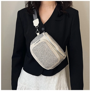 Detail of trendy off-white sling bag with silver metal rivets and wide striped strap