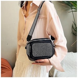 Detail of black punk crossbody bag with silver studs and striped wide shoulder strap