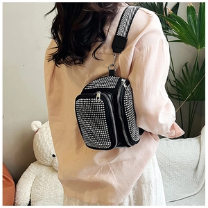 Detail of black rhinestone bucket bag with silver studs and striped shoulder strap
