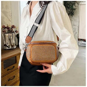 Detail of camel suede crossbody bucket bag with dense silver rhinestones and chevron strap