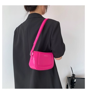 Close-up of a magenta baguette shoulder bag with fashion text on a black blazer