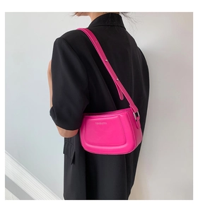 Model wearing a vibrant hot pink leather shoulder bag over a black blazer for contrast