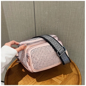 Detail of pink rhinestone bucket bag with sparkling crystals and wide woven shoulder strap