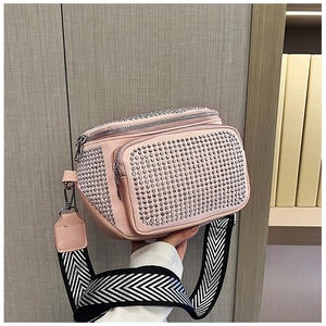 Close-up of pink bucket bag featuring shiny silver rhinestones and a wide woven strap