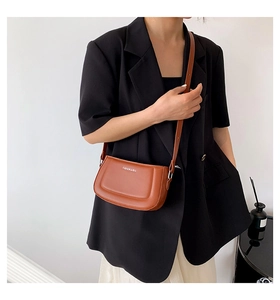 Brown faux leather crescent bag worn by model with FASHION & RYX lettering on the side
