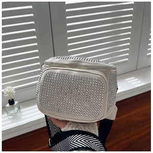 Detail of silver rhinestones and chevron woven strap on white bucket crossbody bag
