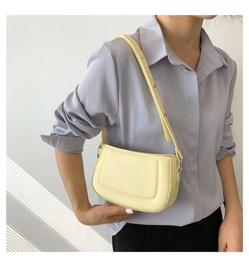 Detail of the yellow leather shoulder bag with FASHION & RYX text worn by a model
