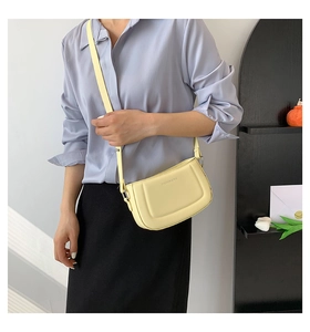 Detail of pale yellow leather shoulder bag with U-shaped quilting and adjustable strap