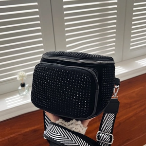 Close-up of black rhinestone bucket bag featuring dual zippers and woven strap